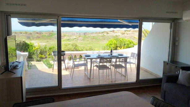 Una habitación con un gran ventanal corredero que da a un espacio exterior con mesa y sillas.