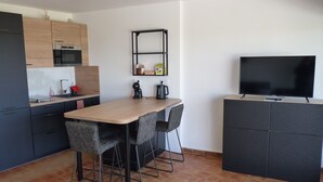 Una cocina moderna con encimera de madera, horno empotrado y un televisor negro sobre un mueble de madera.