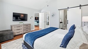 Ein Schlafzimmer mit Bett, Schminktisch, Fernseher und Deckenventilator.