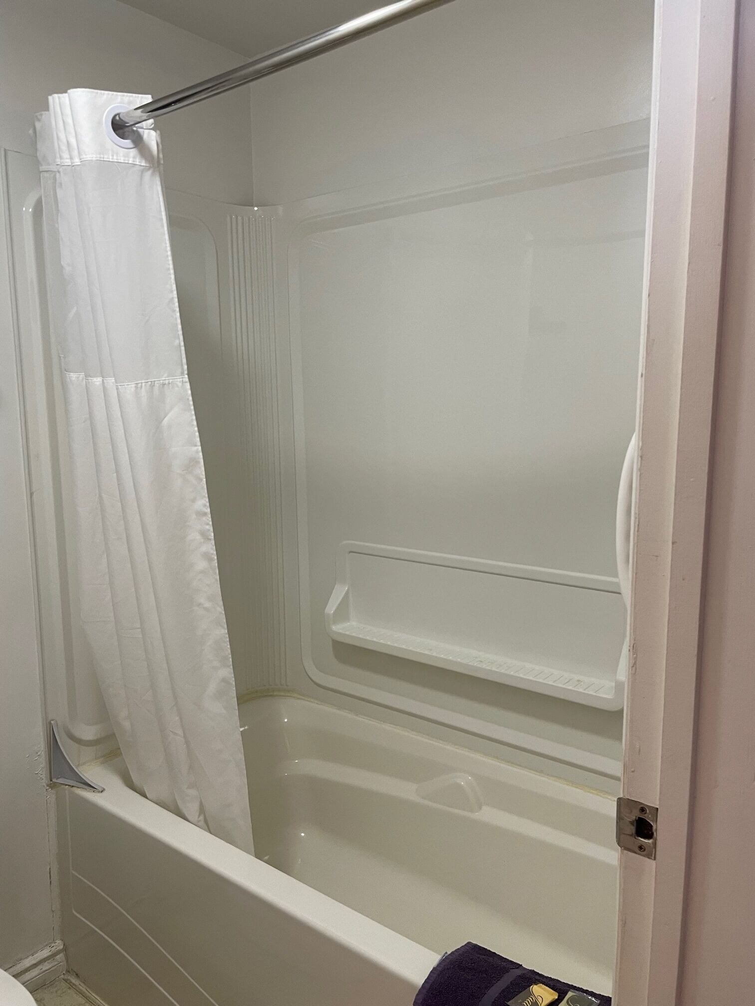 Un baño con bañera, cortina de ducha y estante.