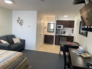 A compact hotel room with a bed, a sofa, a dining table, and a kitchenette. - Shellbrook Motel (Shellbrook)