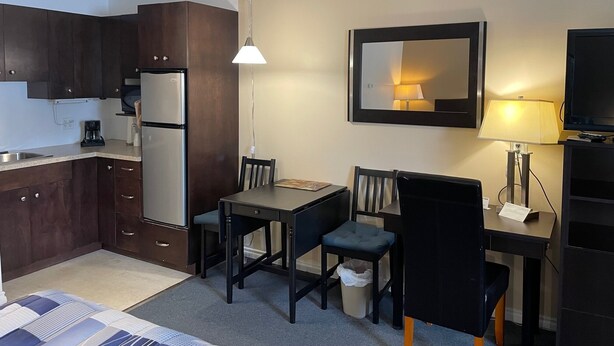 Een compact hotelkamer met een kitchenette, een eethoek, een bed en een televisie.