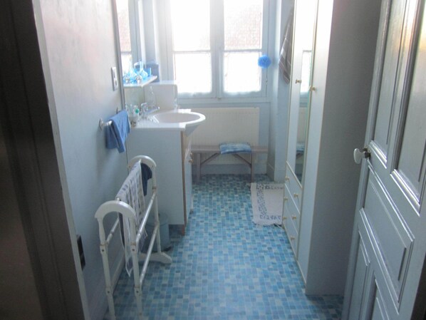 A bathroom with a white sink, a window, a blue-tiled floor, and a white radiator.
