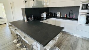 Une cuisine moderne dotée d’un îlot central, de tabourets de bar, d’un four à micro-ondes et d’un évier.