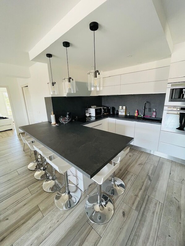 Una cucina moderna con isola centrale, sgabelli da bar, un forno a microonde e un lavello.