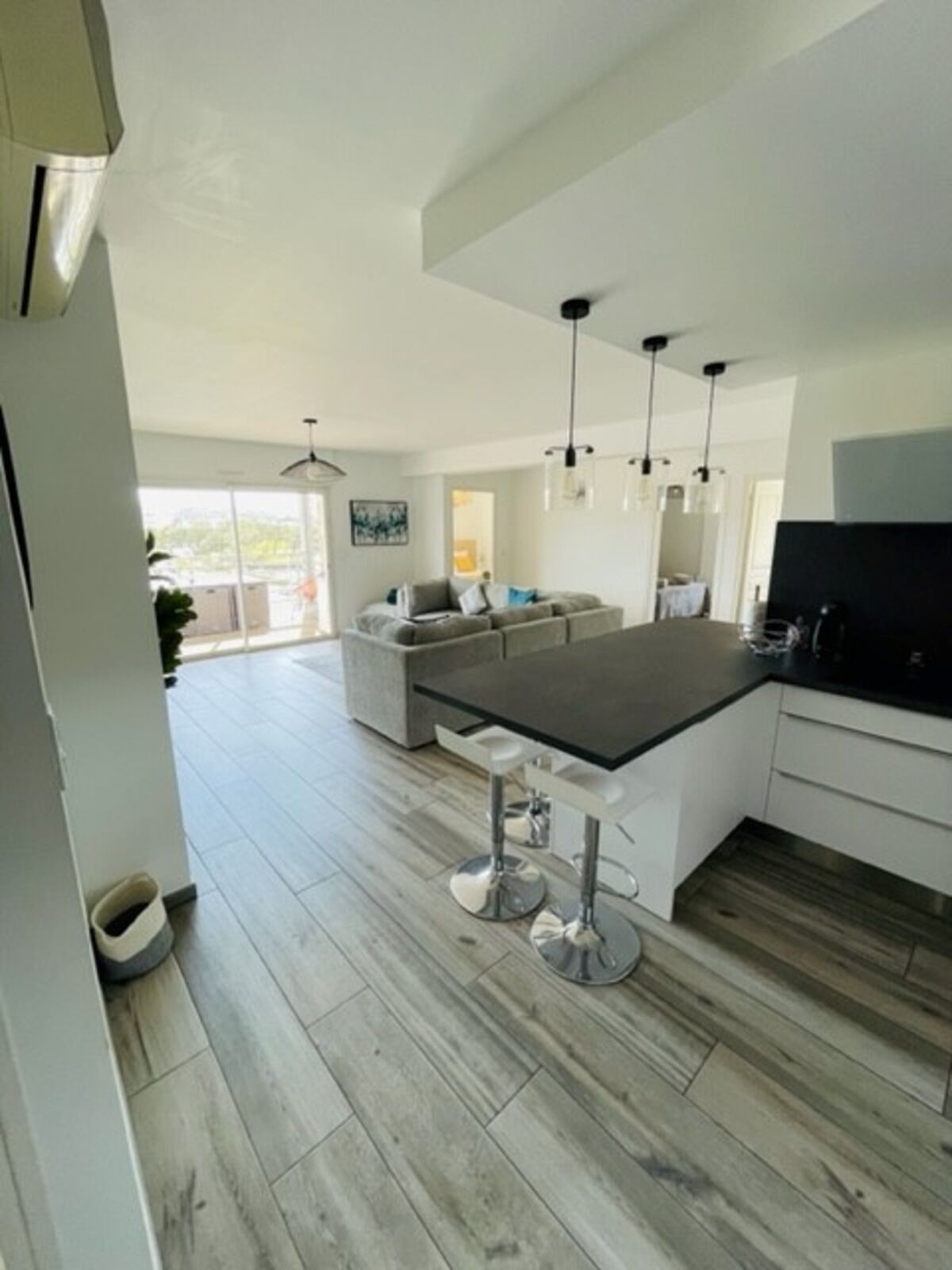 A modern kitchen with a central island, bar stools, and pendant lighting.
