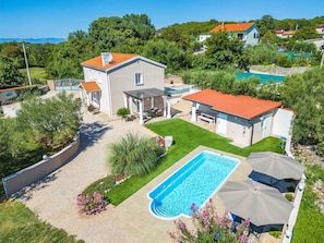Una proprietà residenziale con piscina, patio coperto e prato curato.