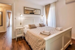 A bedroom with a bed, nightstands, a mirror, and a window with curtains.