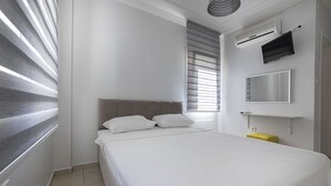 Un dormitorio con una cama grande, una mesita de noche, un espejo y una ventana con persianas.