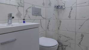 Un baño con inodoro blanco, un lavabo con grifo y una zona de ducha.