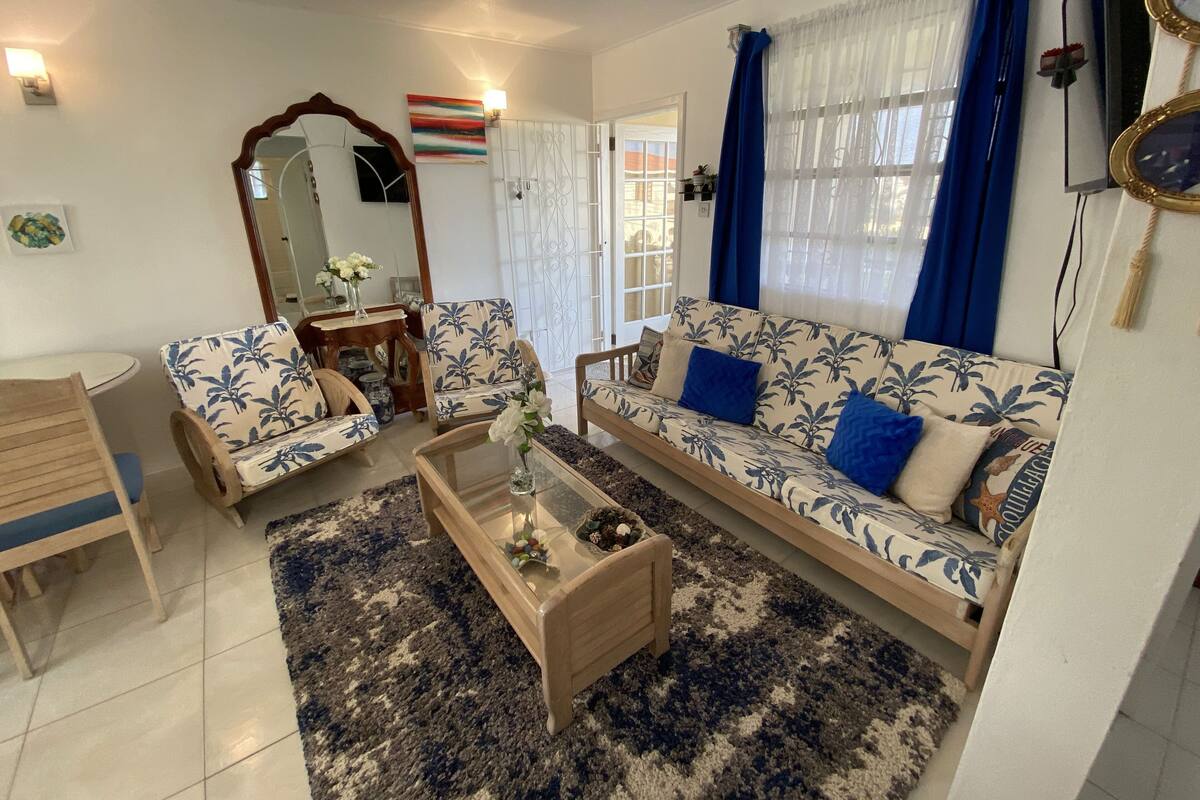 A living room with a sofa, armchairs, a coffee table, and a rug.