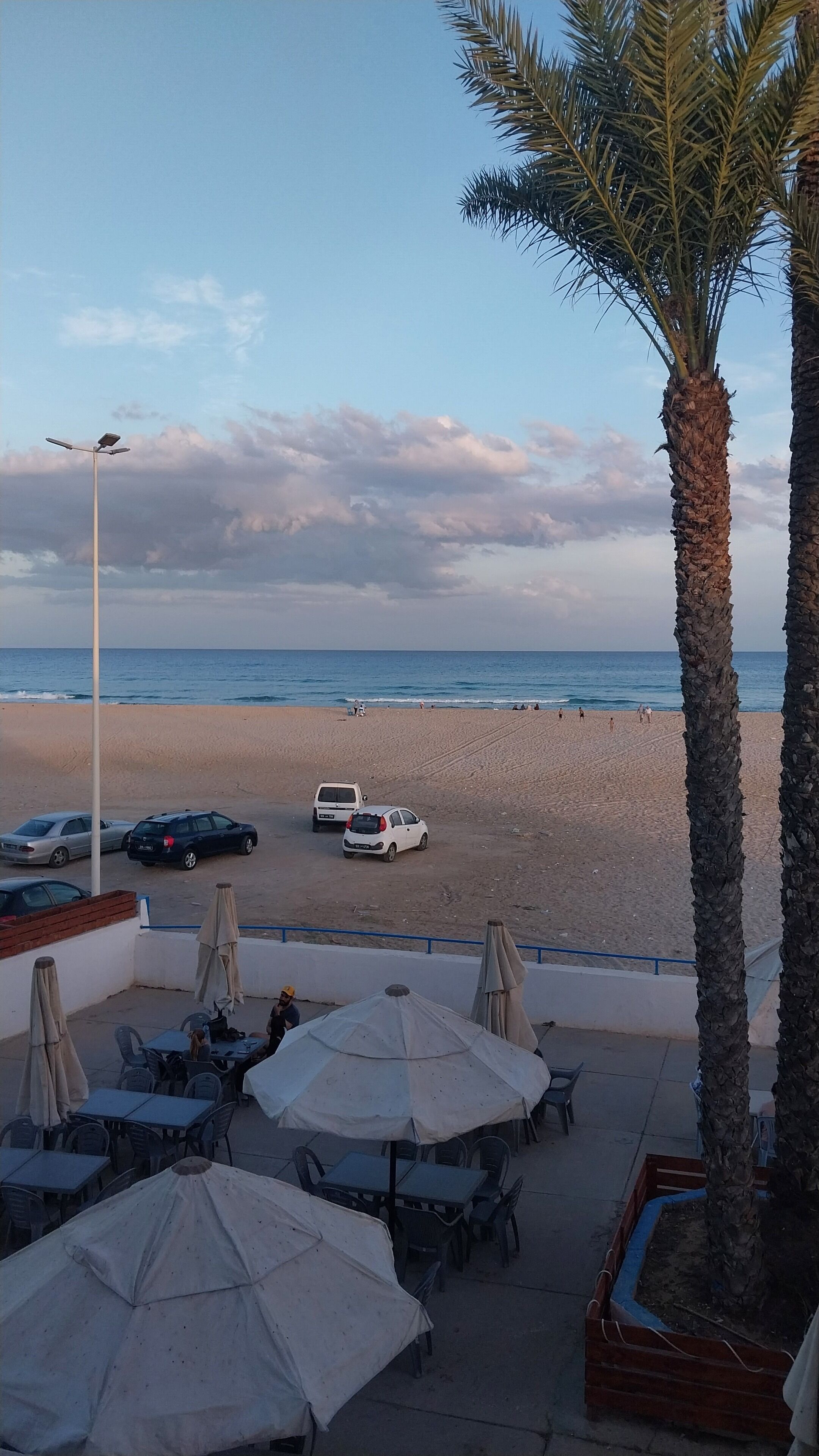 Ein Café direkt am Strand mit Außenplätzen und Sonnenschirmen, mit Blick auf den Strand und den Ozean.