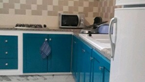 Eine Küche mit taubenblauen Schränken, einer Mikrowelle, einem Herd und einem Kühlschrank.