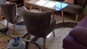 Ein gemütliches Wohnzimmer mit Backsteinwand, Kamin, Sofa, Couchtisch und einem Fenster mit gemusterten Vorhängen.