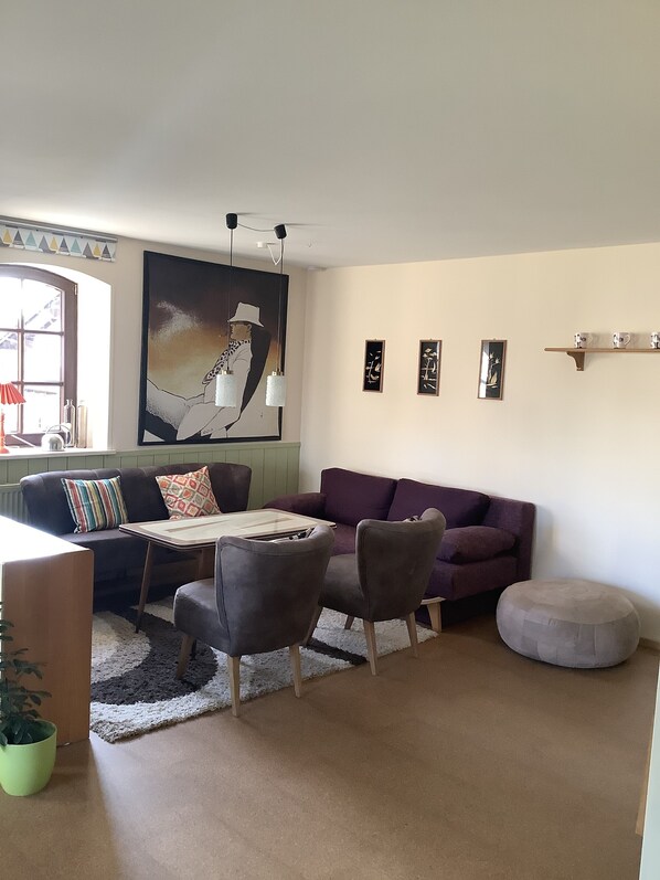 Un salon comprenant un canapé, des fauteuils, une table basse et un grand tableau accroché au mur.