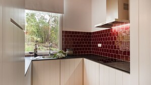 Una cocina moderna con armarios blancos, encimera negra y salpicadero con azulejos rojos.