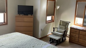 Makuuhuone, jossa on sänky, lipasto, tuoli, kattotuuletin ja televisio.