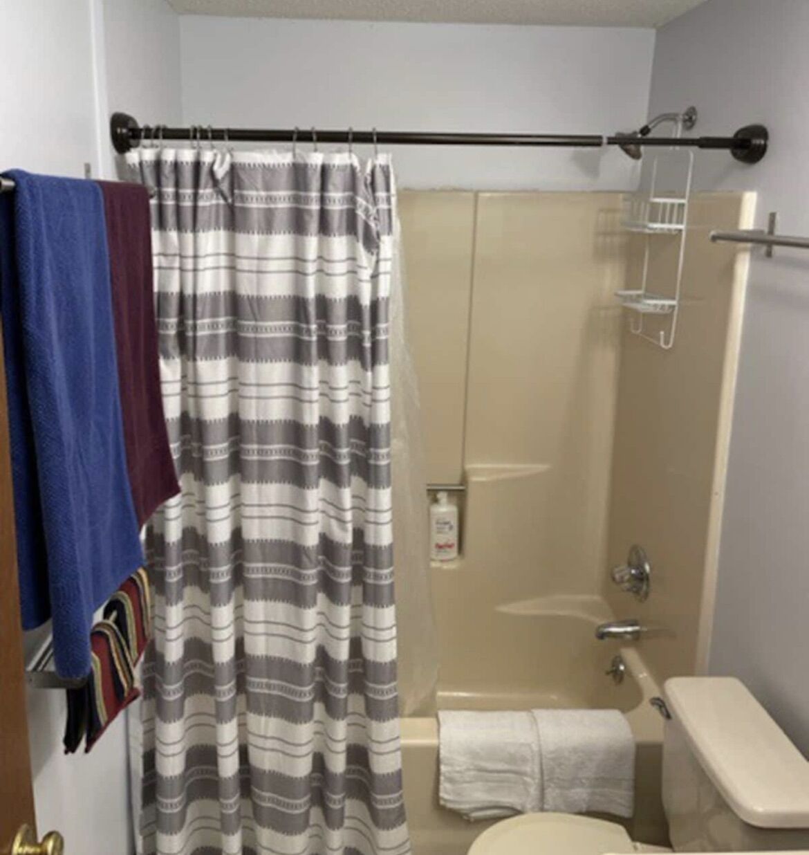 Un baño con ducha, inodoro y perchero para toallas.