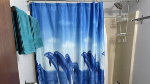 Kylpyhuone, jossa on delfiinejä kuvaava suihkuverho, wc-istuin, pesuallas ja pyyhekoukku.
