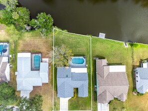 Vue aérienne d’un quartier résidentiel avec des maisons, une piscine et une cour clôturée.