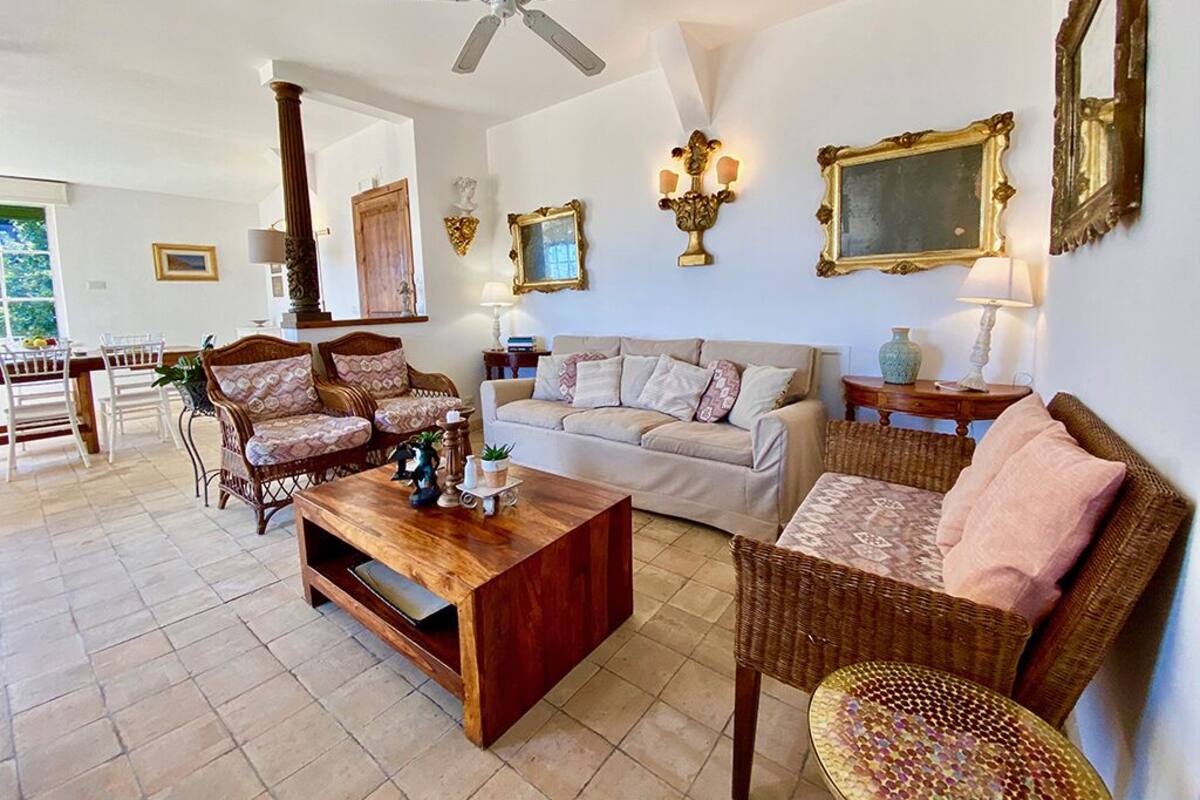 A spacious living room with a ceiling fan, a sofa, a coffee table, and wicker furniture.