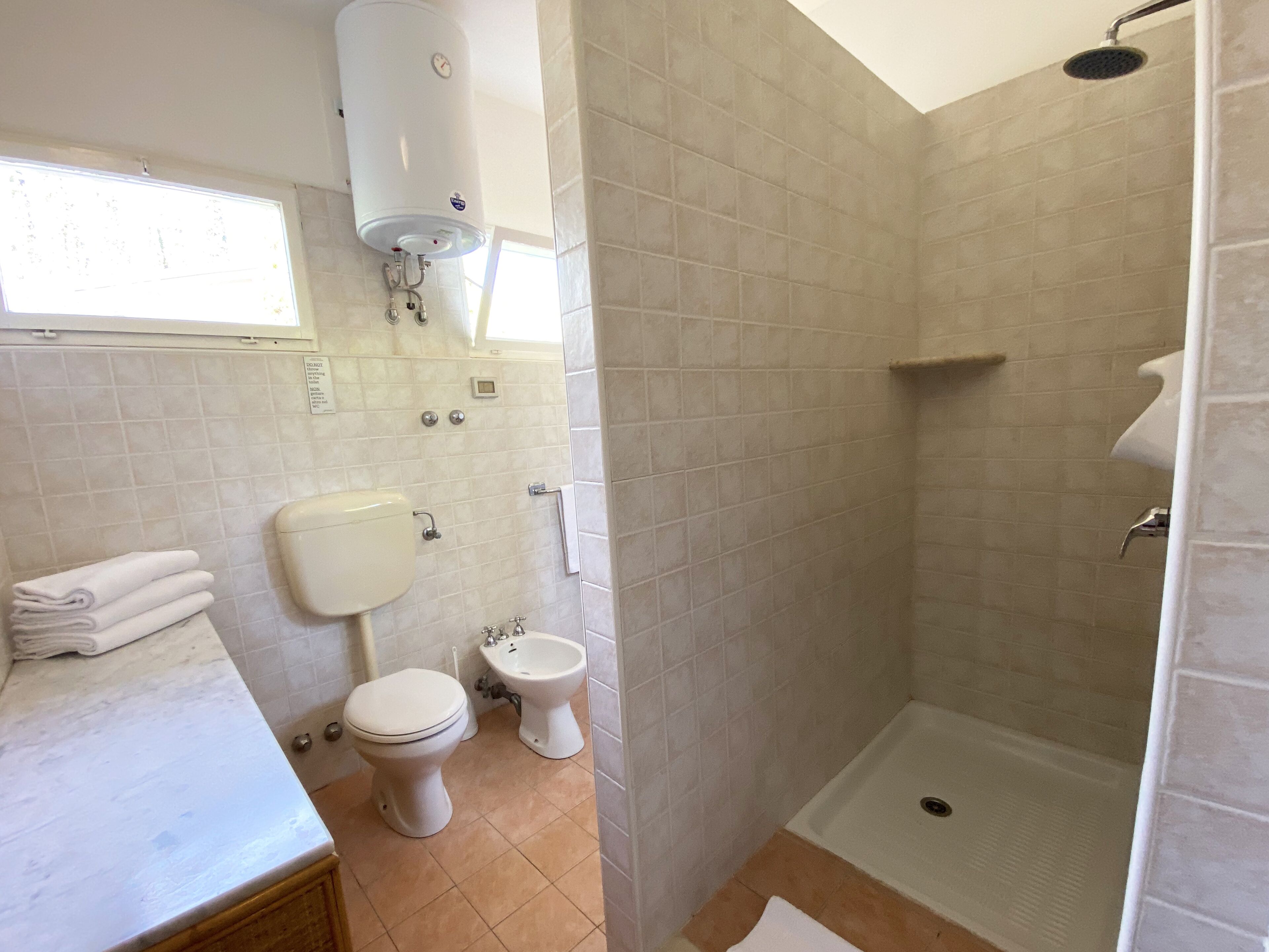 Ein Badezimmer mit Toilette, Bidet und einer barrierefreien Dusche.