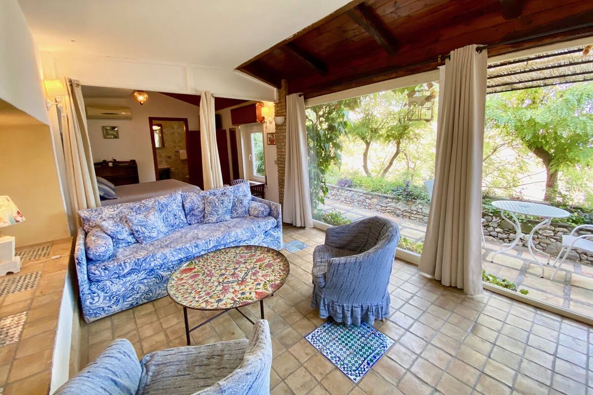 A cozy room with a patterned sofa, a small round table, and a rattan chair.