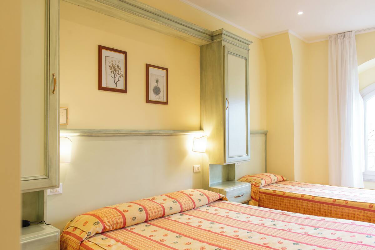 A hotel room with two beds, a mirror, and a window with curtains.