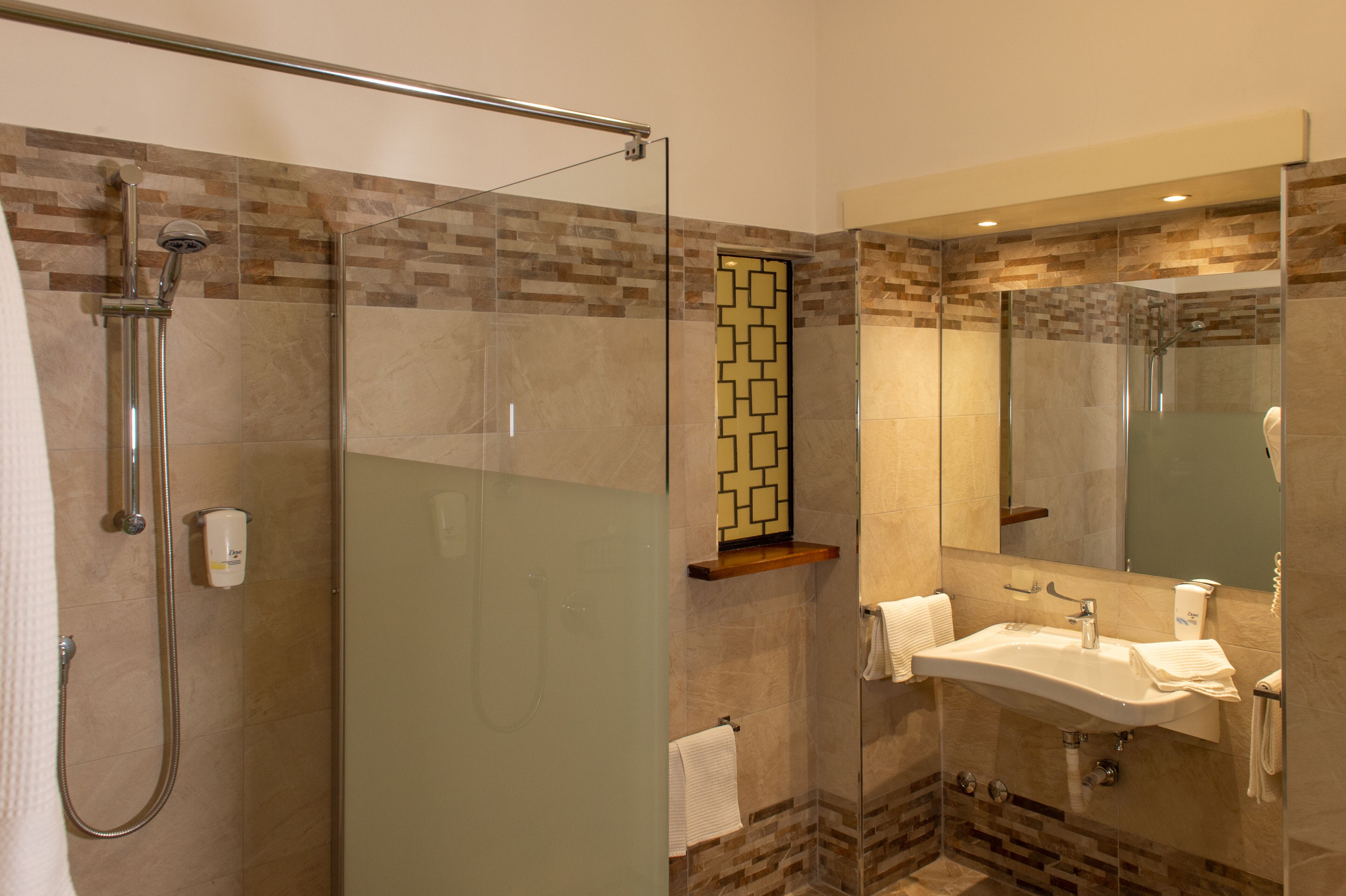 A modern bathroom with a glass-enclosed shower, a sink with a mirror, and a towel rack.