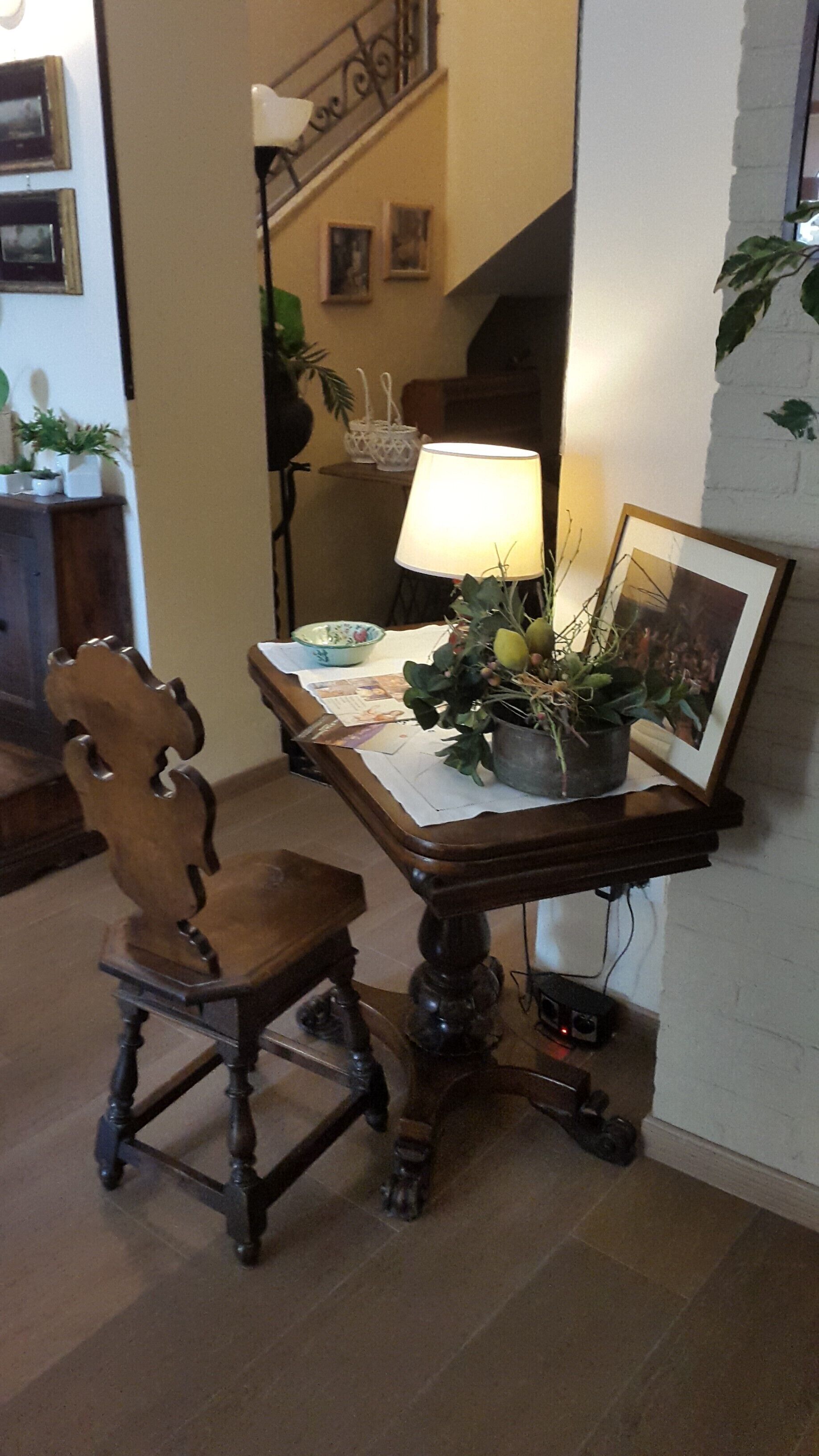 A dining table with a lamp, a chair, and a potted plant.
