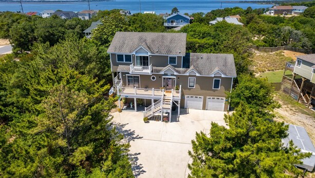 A large two-story house with a covered front porch, a garage, and a view of the ocean. - Venus Studio: Hottub, King Bed, Kayak, Bikes, SUP,  (Kitty Hawk)