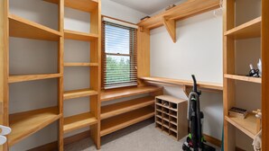 A walk-in closet with multiple wooden shelves and a built-in bench. - Venus Studio: Hottub, King Bed, Kayak, Bikes, SUP,  (Kitty Hawk)