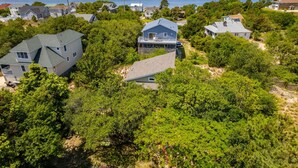 A residential area with houses surrounded by dense greenery and a body of water in the background. - Venus Studio: Hottub, King Bed, Kayak, Bikes, SUP,  (Kitty Hawk)