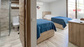 Una habitación de hotel con dos camas, ducha y suelo de madera.