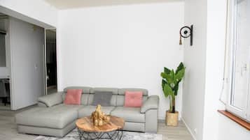 A living room with a sectional sofa, a round wooden coffee table, and a large potted plant.