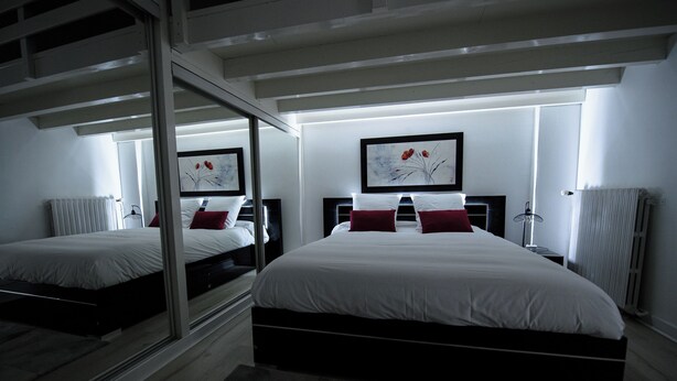 A modern hotel room with two beds, a large mirror, and artwork on the walls. - SPACIOUS, EXCEPTIONAL APARTMENT (Épinal)