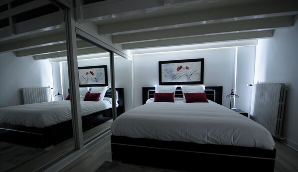 A modern hotel room with two beds, a large mirror, and artwork on the walls. - SPACIOUS, EXCEPTIONAL APARTMENT (Épinal)