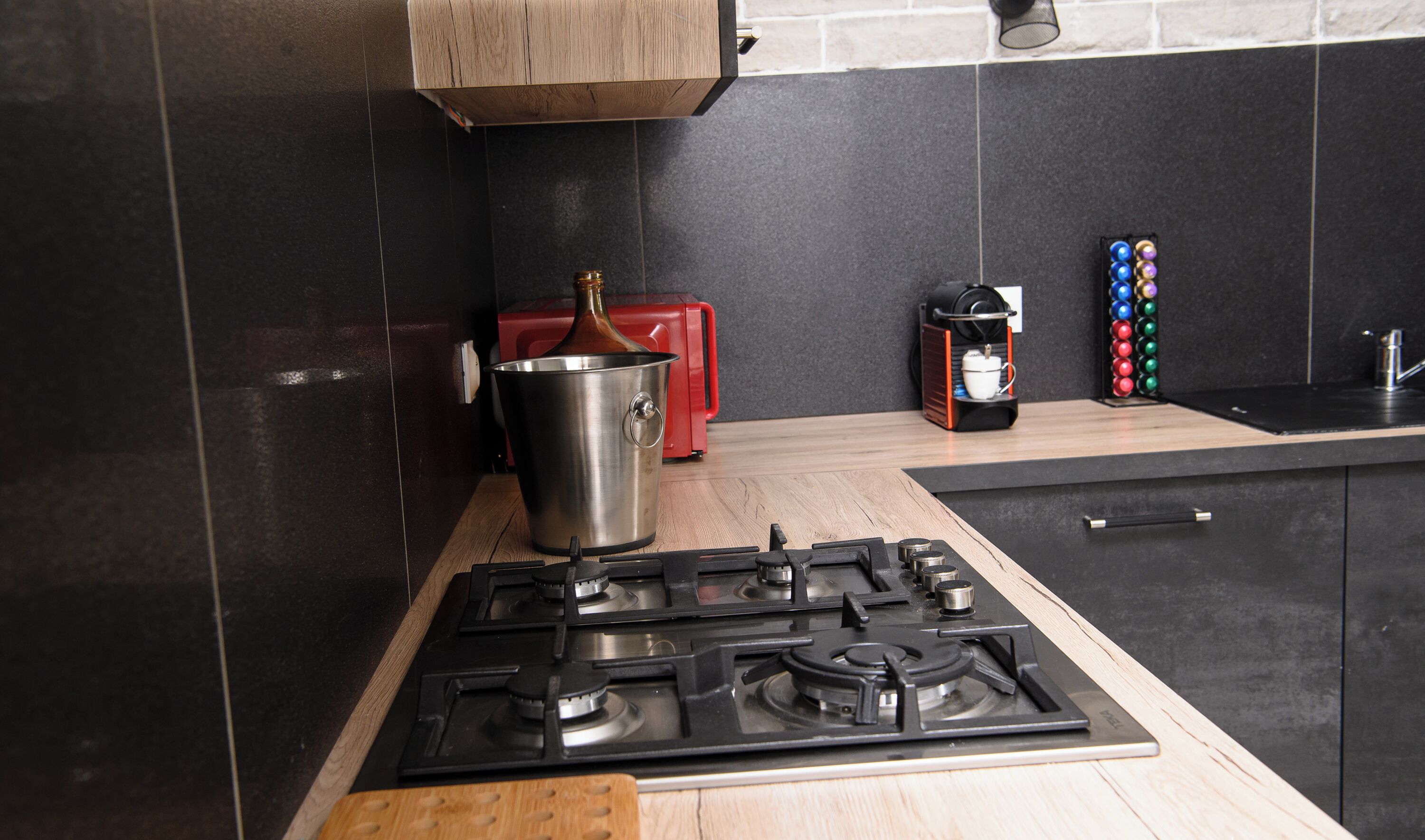 A modern kitchen with a gas stove, a red toaster, and a coffee machine.
