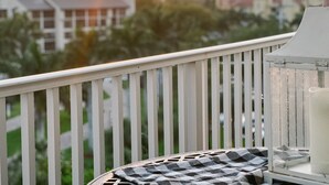 A balcony with a checkered tablecloth, a white railing, and a clear view of the sunset over a residential area. - ELEVATE IN THE SUN! A Renovated Beachfront Condo! (Fort Myers Beach)
