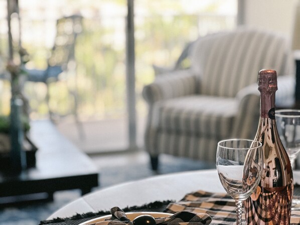 A table with a bottle of wine, a glass, and a checkered placemat.