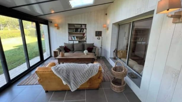 A modern living room with a sofa, a coffee table, and a bookshelf. There are large windows and a skylight. - Exceptional setting, many points of interest (Prailles-La Couarde)