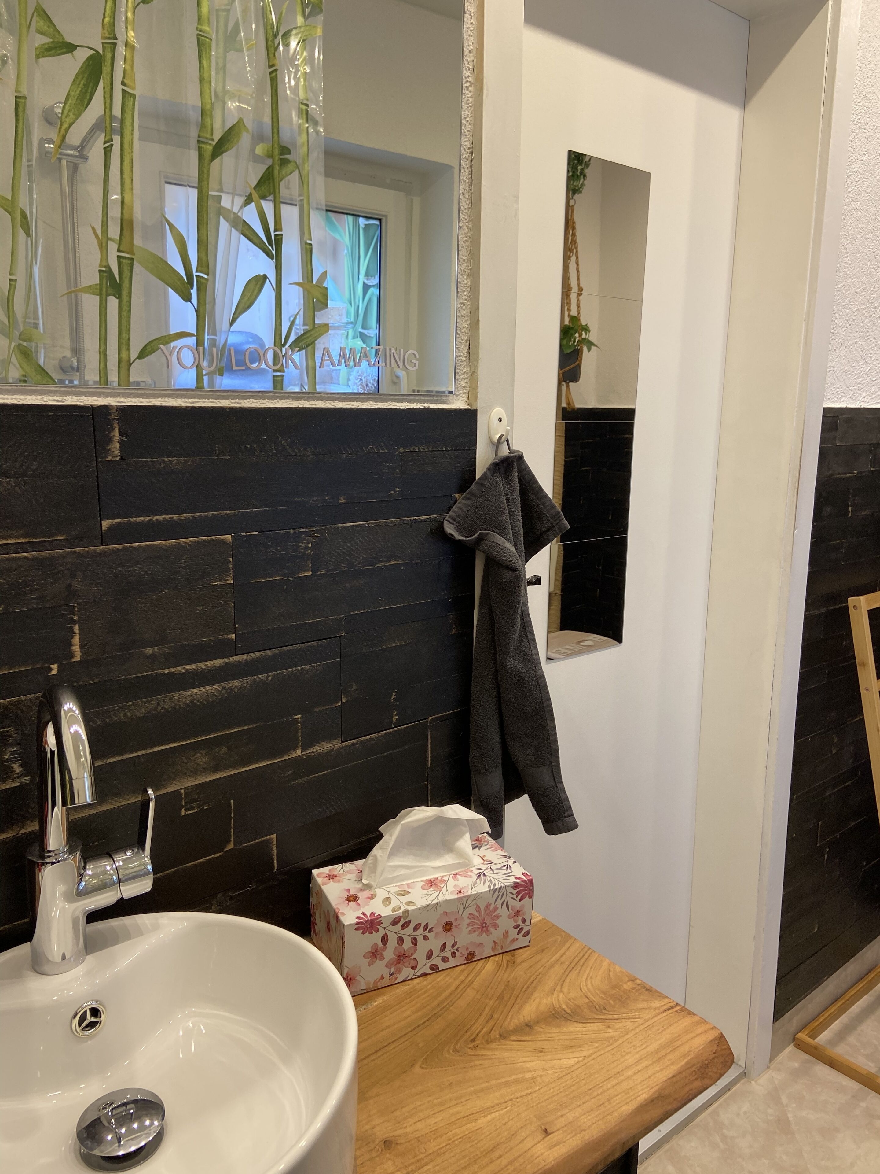 Ein Badezimmer mit einem weißen Waschbecken, einem Spiegel, einem Handtuchhalter und einer Holz-Kommode.