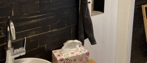 Ein Badezimmer mit einem weißen Waschbecken, einem Spiegel, einem Handtuchhalter und einer Holz-Kommode.