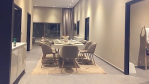 Un espace repas moderne avec une table rectangulaire, plusieurs chaises et une palette de couleurs neutres.