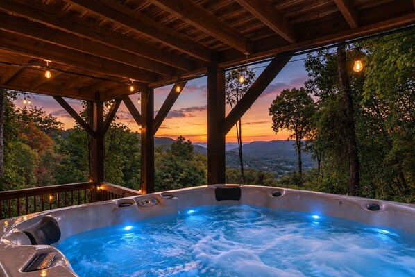 A hot tub with a view of a sunset and mountains.