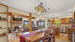 A spacious living room with a fireplace, wooden furniture, and a dining area with a red and black checkered tablecloth. - Long- & Short-Range Views/King Beds/Fireplace/Fire Table/Game Room (Maggie Valley)