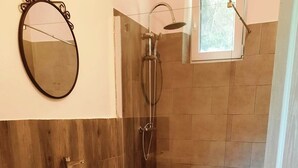 Et badeværelse med en hvid vask, toilet og bruseområde.