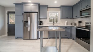 A modern kitchen with grey cabinets, stainless steel appliances, and a central island. - NEW! Completely renovated 2bed/1bath UPTOWN home! (Hot Springs National Park)