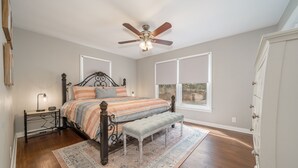 A bedroom with a bed, a bench, a nightstand, a ceiling fan, and a window. - NEW! Completely renovated 2bed/1bath UPTOWN home! (Hot Springs National Park)