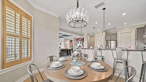 Un espace repas avec une table ronde dressée pour six personnes, entourée de chaises en métal.